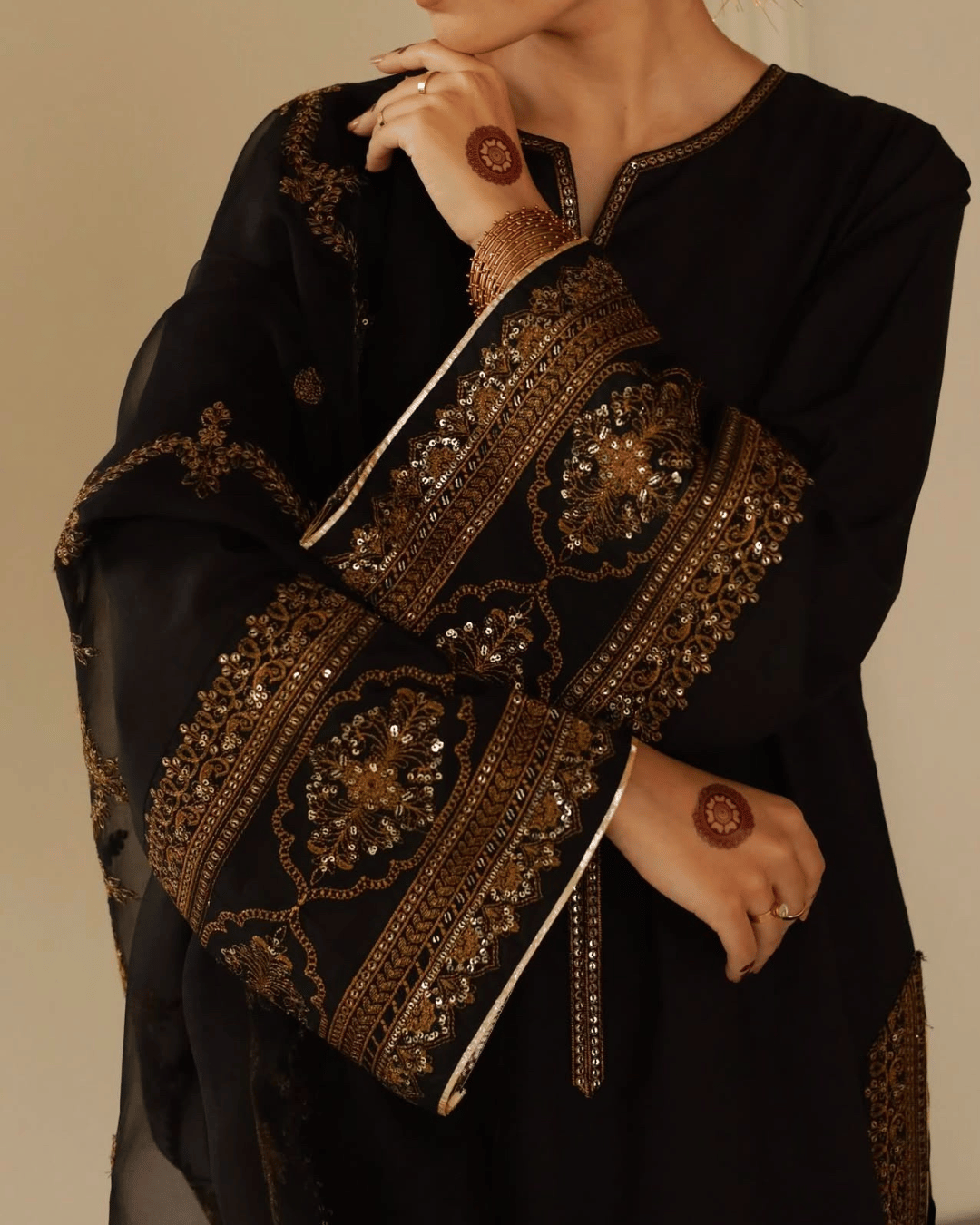 Black embroidered Pakistani dress with gold detailing, matching dupatta, and henna design