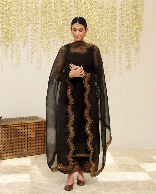 Woman in black and gold embroidered salwar suit with dupatta, traditional Indian attire.