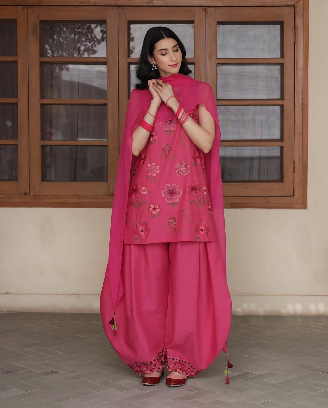 Woman in vibrant pink floral embroidered salwar kameez and dupatta, traditional outfit style