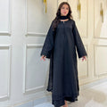 Woman wearing black embroidered abaya dress with dupatta, standing indoors